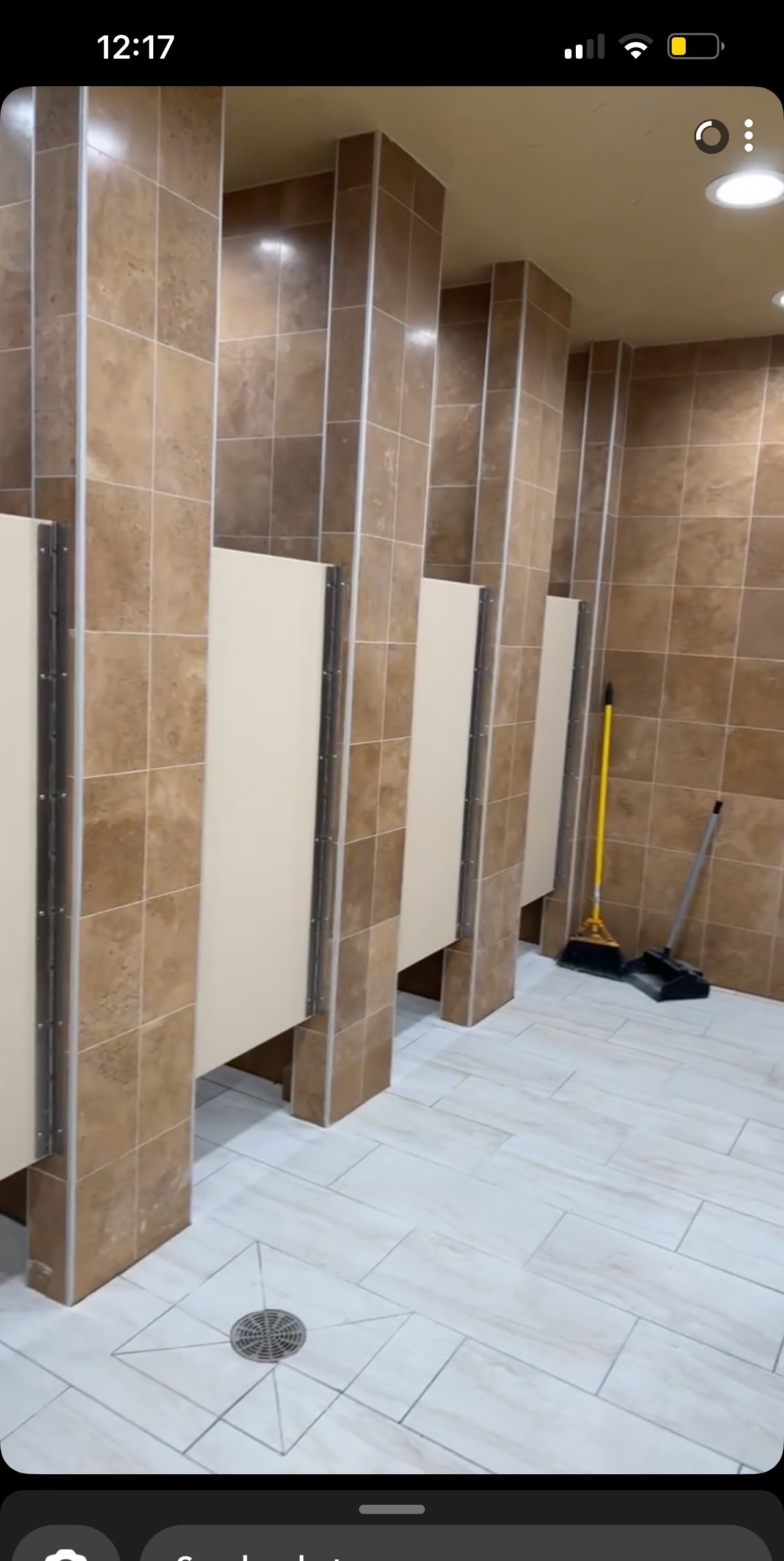 Commercial restroom with stone-look wall tile and light floor tile, precision cuts around floor drain